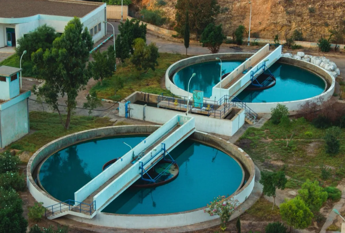 Aerial view of a water treatment plant with two circular clarifier tanks and mechanical rotating arms